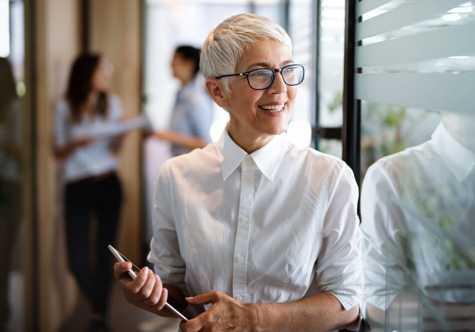 Portrait of senior business woman holding digital tablet while standing at office.